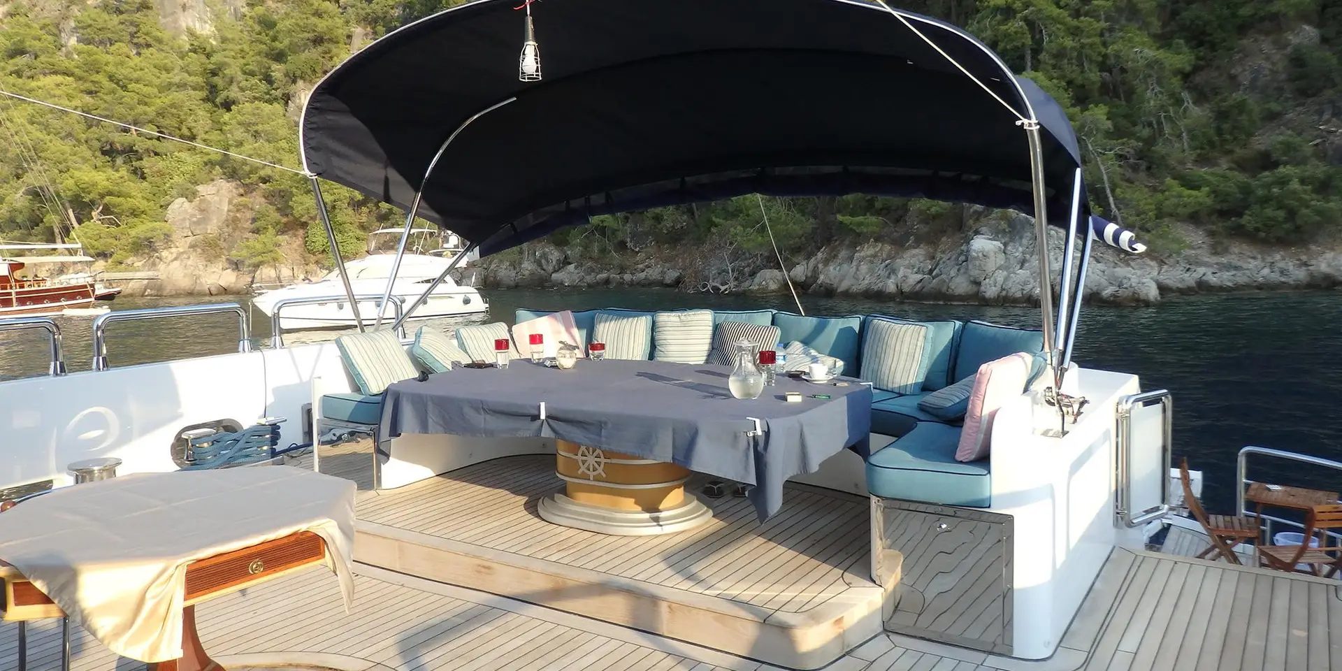 Sheltered exterior dining table with blue seating on board M/Y DESTINY
